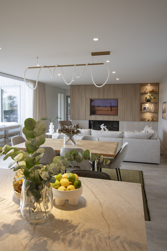This is an example of a Large Scandinavian Formal Open Concept living room in Christchurch With Brown Walls, Light Hardwood Floors, a Ribbon Fireplace, a Tile Fireplace Surround, a Concealed TV and Brown Floor.