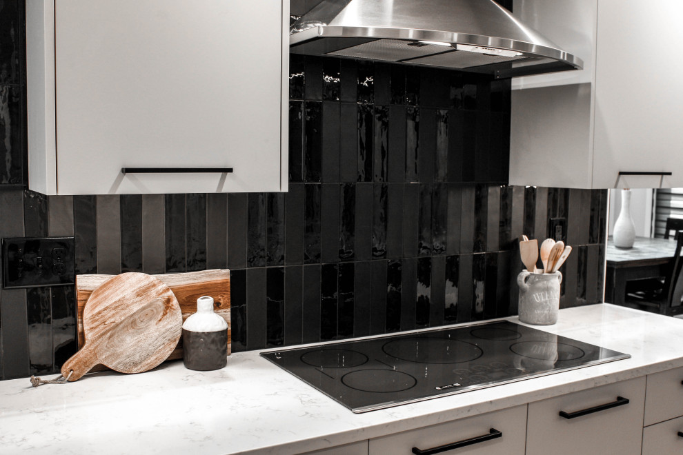 Пример оригинального дизайна: кухня в стиле модернизм с плоскими фасадами, серыми фасадами, черным фартуком, фартуком из керамогранитной плитки, техникой из нержавеющей стали и столешницей из кварцевого агломерата