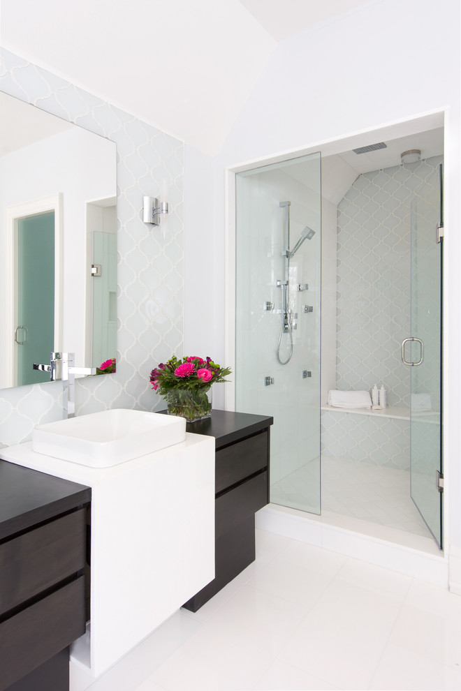 This is an example of a contemporary bathroom in Toronto with a vessel sink, flat-panel cabinets, dark wood cabinets, an alcove shower, blue tile, glass tile and marble floors.
