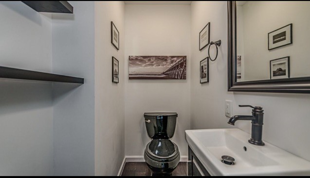 This is an example of a mid-sized transitional powder room in Indianapolis with raised-panel cabinets, black cabinets, a two-piece toilet, white walls, dark hardwood floors, an integrated sink, solid surface benchtops and brown floor.