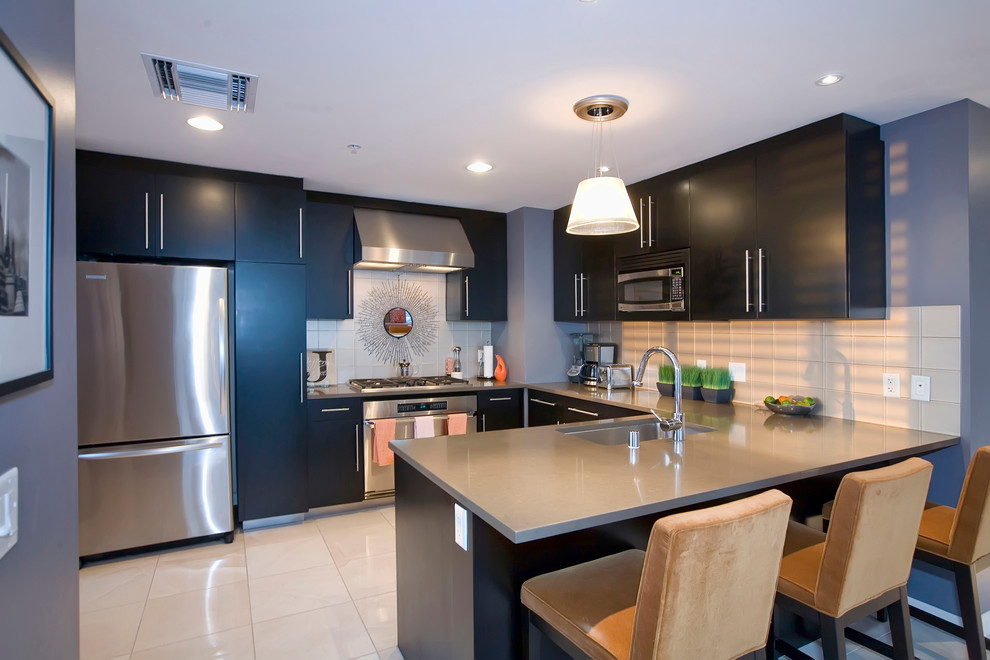 This is an example of a contemporary u-shaped separate kitchen in Phoenix with an undermount sink, flat-panel cabinets, black cabinets, stainless steel appliances and no island.