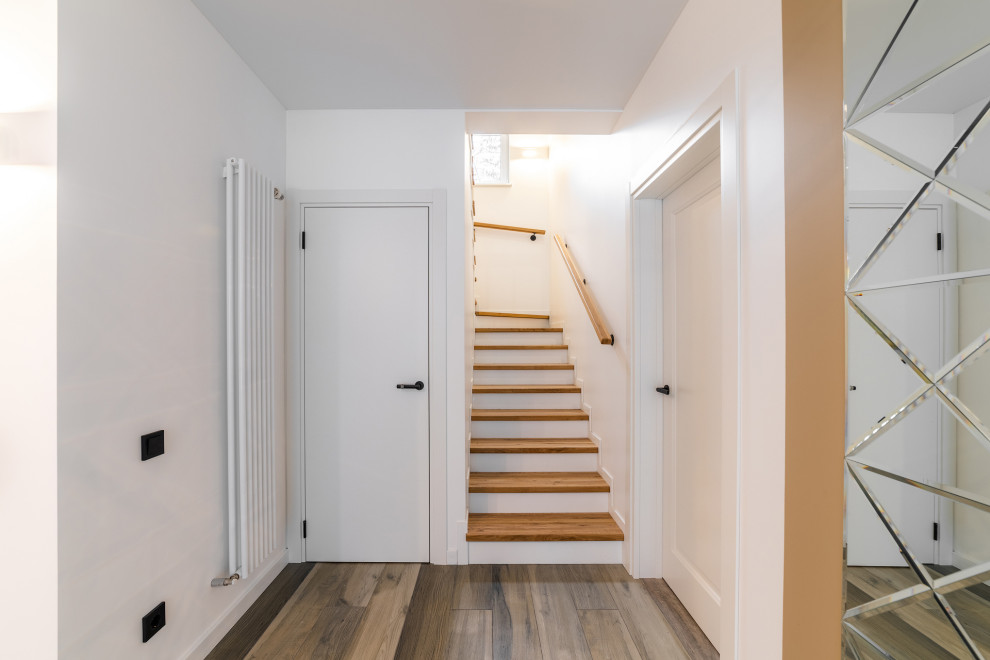 Cette image montre un escalier minimaliste en U avec des marches en bois peint, un garde-corps en bois et rangements.