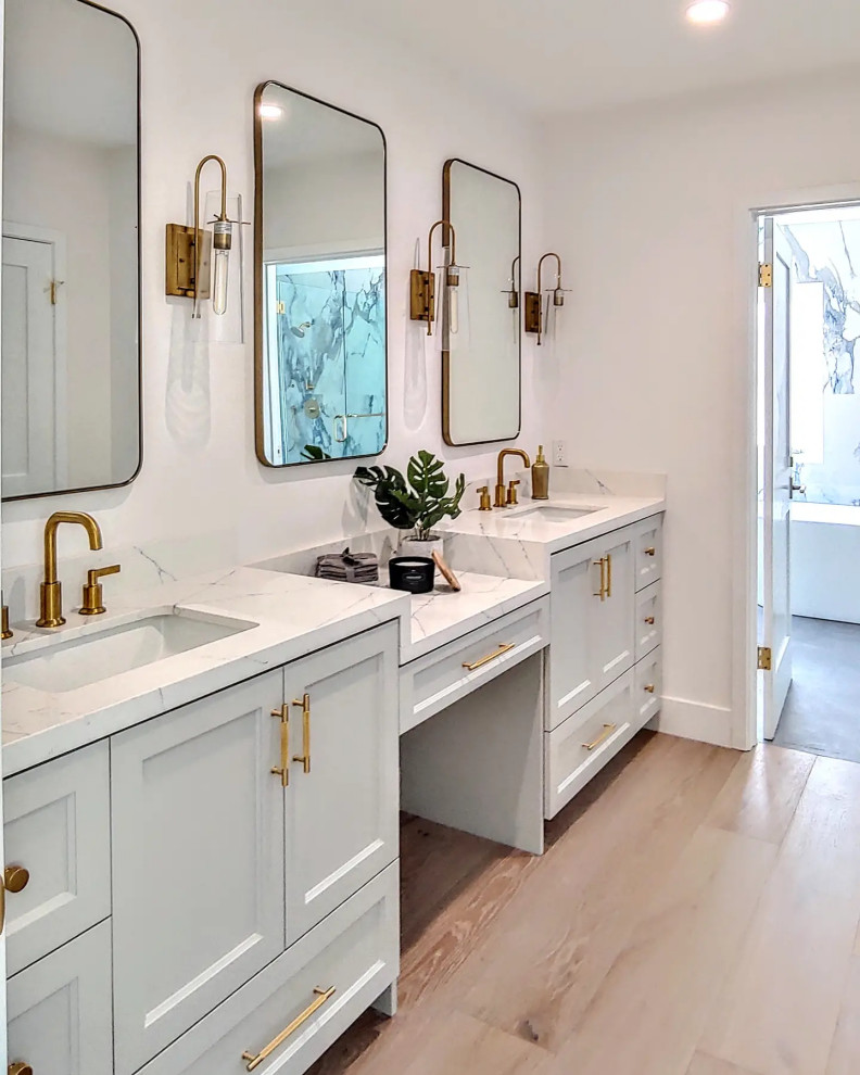 Diseño de cuarto de baño principal, doble y a medida moderno de tamaño medio con armarios estilo shaker, puertas de armario grises, suelo de madera clara, encimera de cuarzo compacto y encimeras blancas