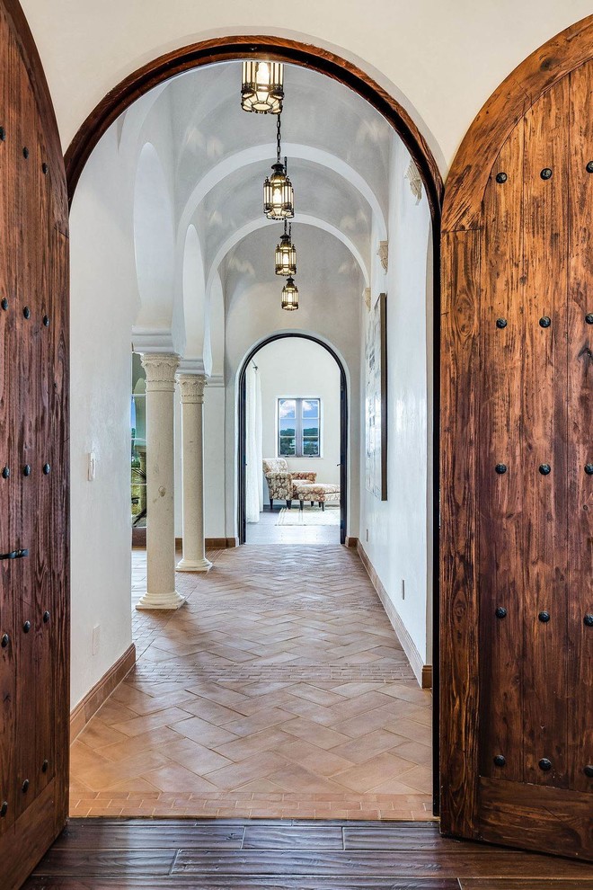Photo of a large mediterranean hallway in Austin with white walls, terra-cotta floors and red floor.