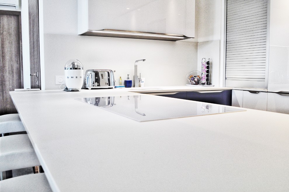 Expansive modern u-shaped eat-in kitchen in Nice with an undermount sink, white cabinets, granite benchtops, white splashback, panelled appliances, with island, grey floor and white benchtop.