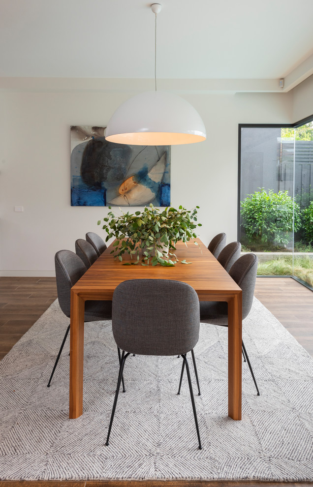 Inspiration for a contemporary dining room in Melbourne with white walls, porcelain floors and brown floor.