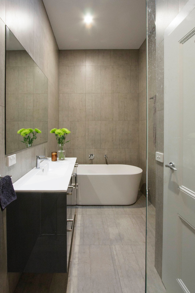Contemporary master bathroom in Melbourne with grey cabinets, a freestanding tub, grey walls and ceramic floors.