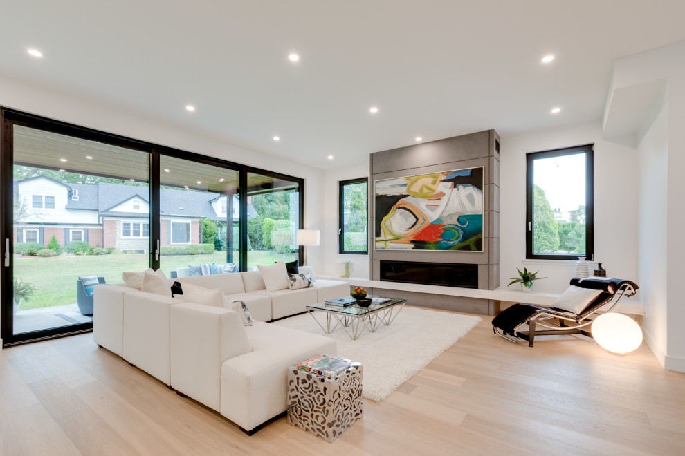 This is an example of a contemporary formal open concept living room in Toronto with white walls, light hardwood floors, a ribbon fireplace, a concrete fireplace surround, no tv and beige floor.