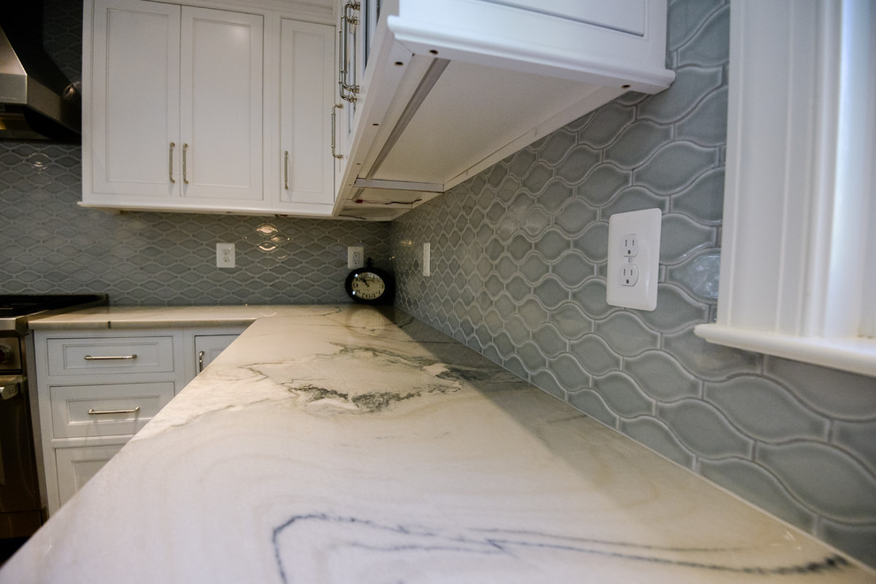 Inspiration for a large transitional u-shaped medium tone wood floor and brown floor eat-in kitchen remodel in DC Metro with a farmhouse sink, recessed-panel cabinets, white cabinets, marble countertops, stainless steel appliances, an island, gray backsplash and porcelain backsplash