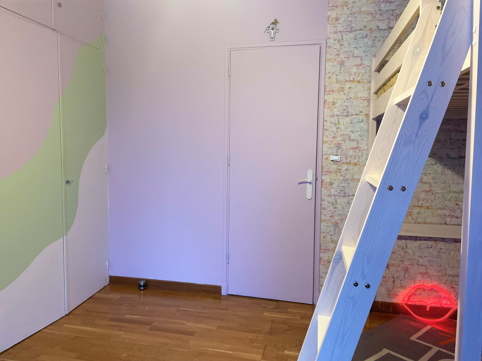 Bild på ett mellanstort barnrum kombinerat med sovrum, med lila väggar och ljust trägolv