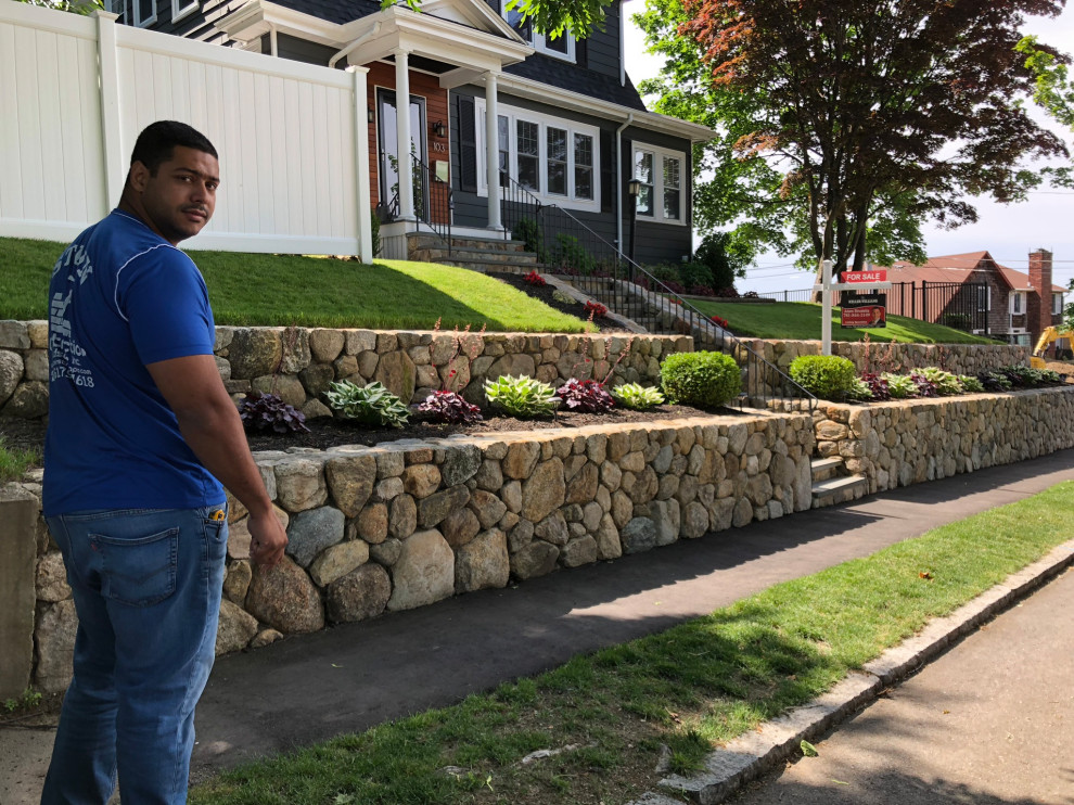 Foto di un giardino american style esposto in pieno sole di medie dimensioni e davanti casa in primavera con un muro di contenimento e pavimentazioni in pietra naturale