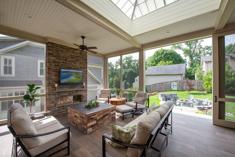 Inspiration for a large transitional backyard verandah in DC Metro with with fireplace, natural stone pavers and a roof extension.