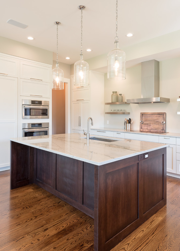 Example of a mid-sized transitional u-shaped dark wood floor and brown floor open concept kitchen design with an undermount sink, shaker cabinets, white cabinets, marble countertops, stainless steel appliances and an island