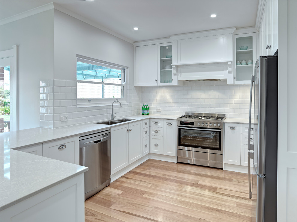 Inspiration for a large contemporary u-shaped eat-in kitchen in Other with an undermount sink, white cabinets, white splashback, stainless steel appliances, medium hardwood floors and no island.