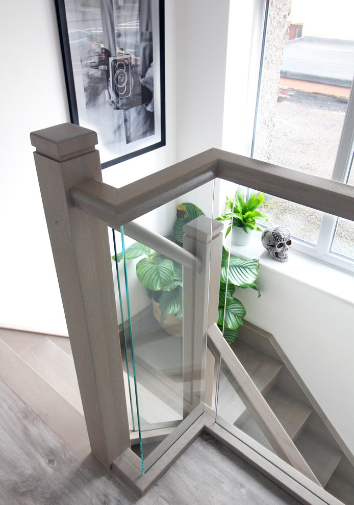 Photo of a mid-sized scandinavian wood l-shaped staircase in West Midlands with wood risers and glass railing.