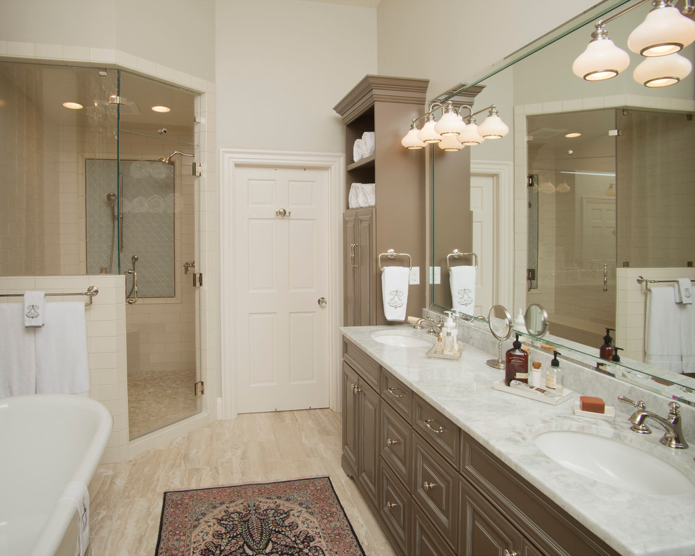 Photo of a large traditional master bathroom in Other with raised-panel cabinets, medium wood cabinets, a freestanding tub, a corner shower, beige tile, white walls, an undermount sink, subway tile, travertine floors, quartzite benchtops, beige floor and a hinged shower door.