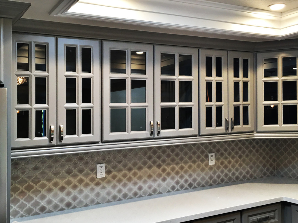 Inspiration for a mid-sized transitional u-shaped medium tone wood floor eat-in kitchen remodel in Orange County with raised-panel cabinets, gray cabinets, quartz countertops, a peninsula, a double-bowl sink, brown backsplash, mosaic tile backsplash and stainless steel appliances