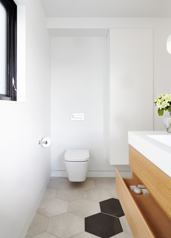 Design ideas for a mid-sized contemporary master bathroom in Toronto with flat-panel cabinets, light wood cabinets, a freestanding tub, an open shower, a one-piece toilet, white tile, stone tile, white walls, porcelain floors, a trough sink and solid surface benchtops.