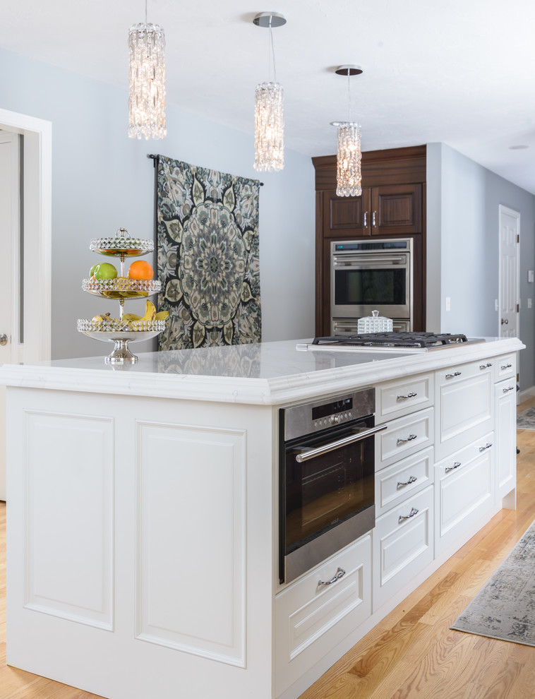 Large traditional l-shaped eat-in kitchen in Boston with an undermount sink, raised-panel cabinets, dark wood cabinets, quartzite benchtops, white splashback, stone slab splashback, stainless steel appliances, light hardwood floors, with island and brown floor.