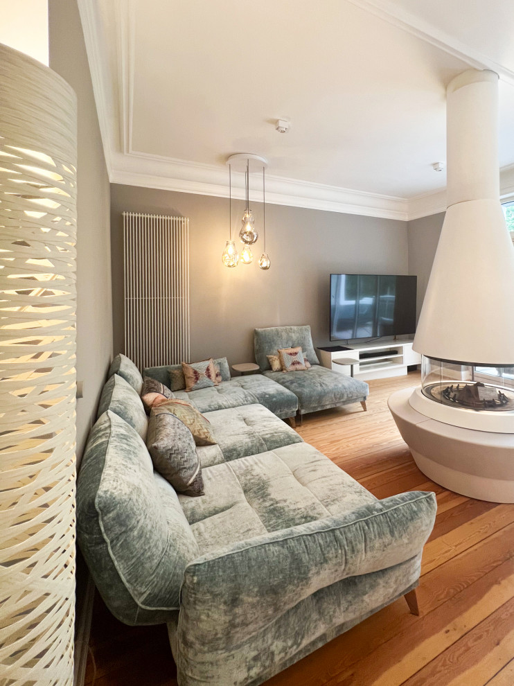 Immagine di un grande soggiorno contemporaneo aperto con pareti marroni, parquet chiaro, stufa a legna, cornice del camino in pietra, TV a parete e pavimento marrone