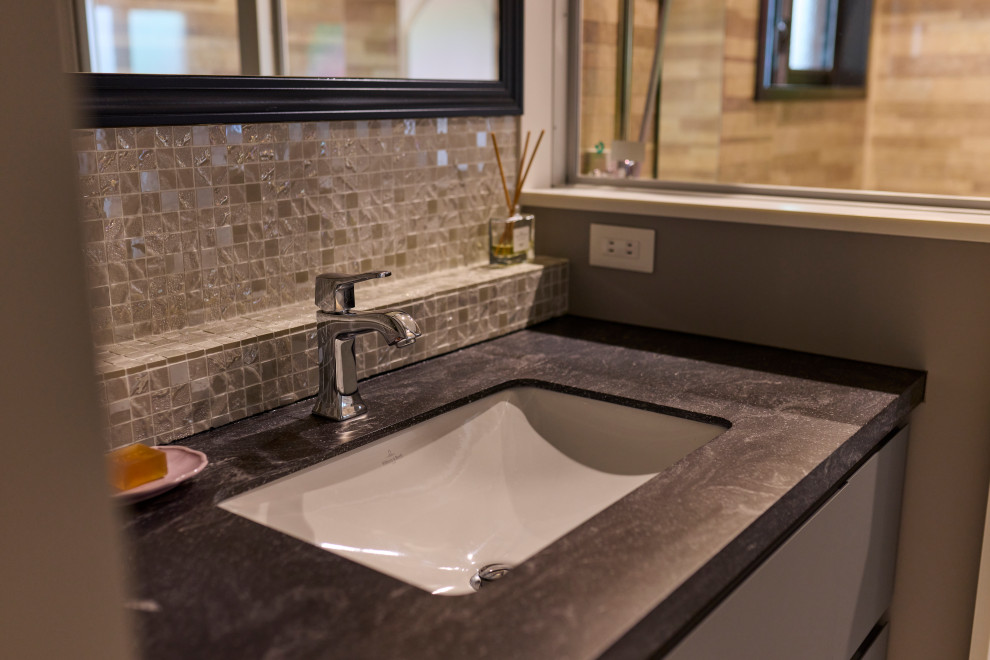 Mittelgroße Klassische Gästetoilette mit grauen Schränken, Toilette mit Aufsatzspülkasten, schwarz-weißen Fliesen, Glasfliesen, schwarzer Waschtischplatte und freistehendem Waschtisch in Osaka