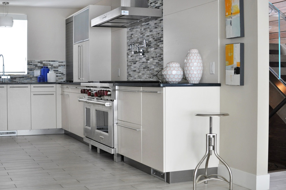 This is an example of a large contemporary u-shaped eat-in kitchen in Grand Rapids with an undermount sink, flat-panel cabinets, white cabinets, multi-coloured splashback, glass tile splashback, stainless steel appliances and no island.