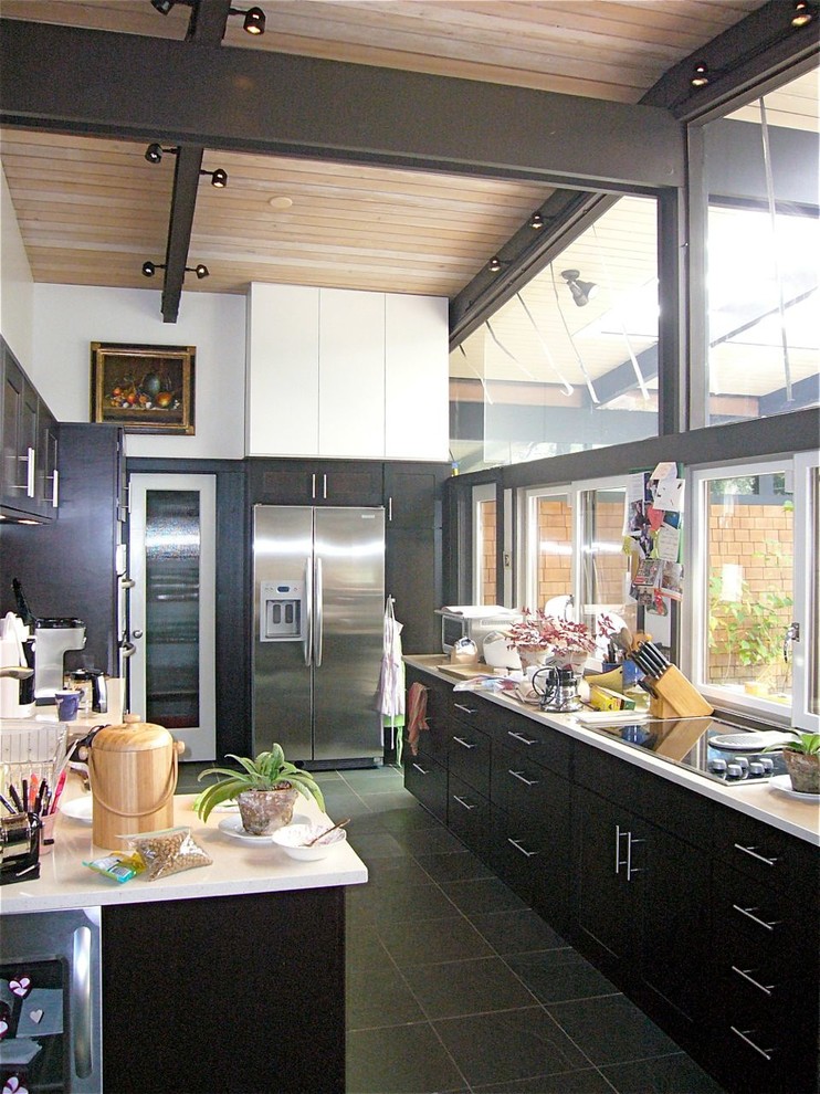 Inspiration for a mid-sized midcentury galley eat-in kitchen in San Francisco with an undermount sink, shaker cabinets, dark wood cabinets, quartz benchtops, stainless steel appliances, slate floors and a peninsula.