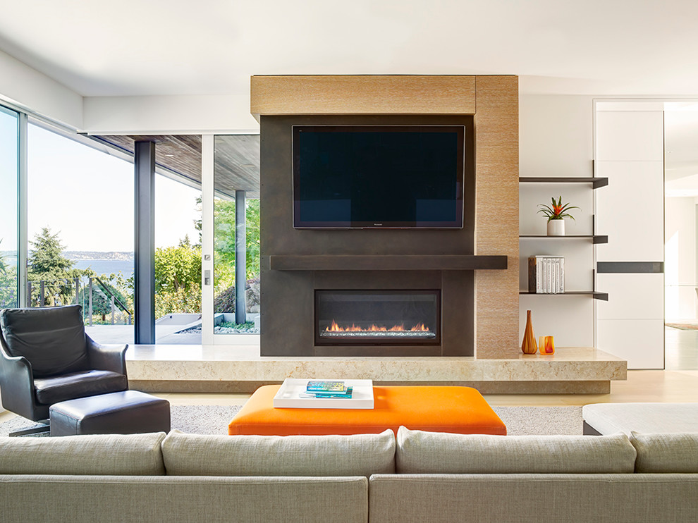This is an example of a contemporary family room in Seattle with white walls, light hardwood floors, a metal fireplace surround, a wall-mounted tv and a ribbon fireplace.