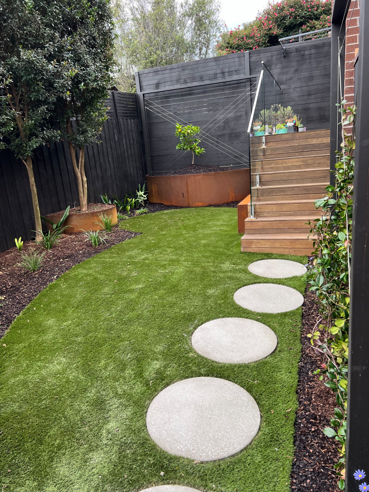 Kleiner, Halbschattiger Moderner Garten im Frühling, hinter dem Haus mit Hochbeet, Betonboden und Holzzaun in Melbourne