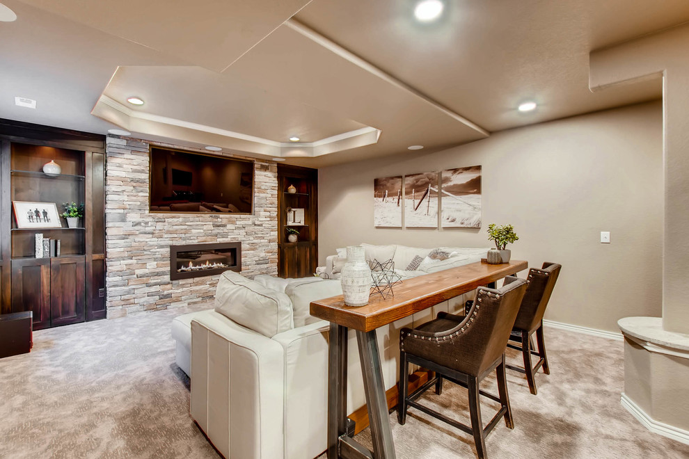 This is an example of a large country fully buried basement in Denver with beige walls, carpet, a ribbon fireplace, a stone fireplace surround and beige floor.