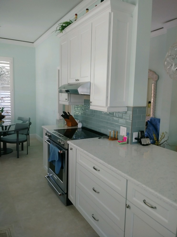 Kitchen - transitional galley kitchen idea with shaker cabinets, white cabinets, quartz countertops, glass tile backsplash and stainless steel appliances