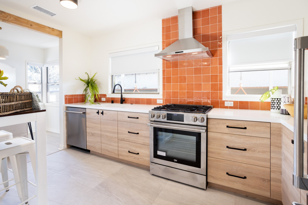 This is an example of a small rural l-shaped enclosed kitchen in Los Angeles with a submerged sink, flat-panel cabinets, light wood cabinets, engineered stone countertops, orange splashback, cement tile splashback, stainless steel appliances, porcelain flooring, no island, grey floors and white worktops.