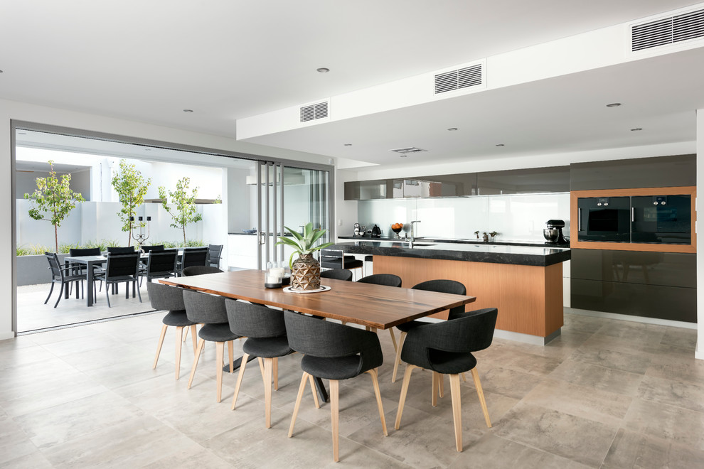 Inspiration for a large contemporary galley open plan kitchen in Perth with an undermount sink, flat-panel cabinets, medium wood cabinets, quartz benchtops, grey splashback, glass sheet splashback, black appliances, porcelain floors and with island.