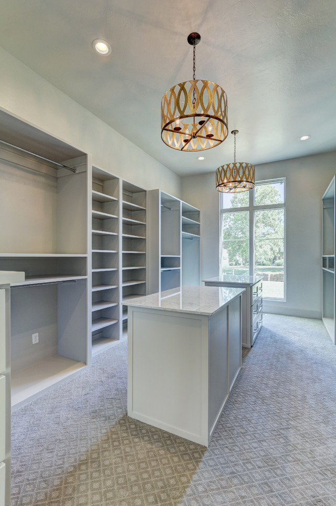 This is an example of an expansive transitional gender-neutral walk-in wardrobe in Oklahoma City with recessed-panel cabinets, white cabinets and carpet.