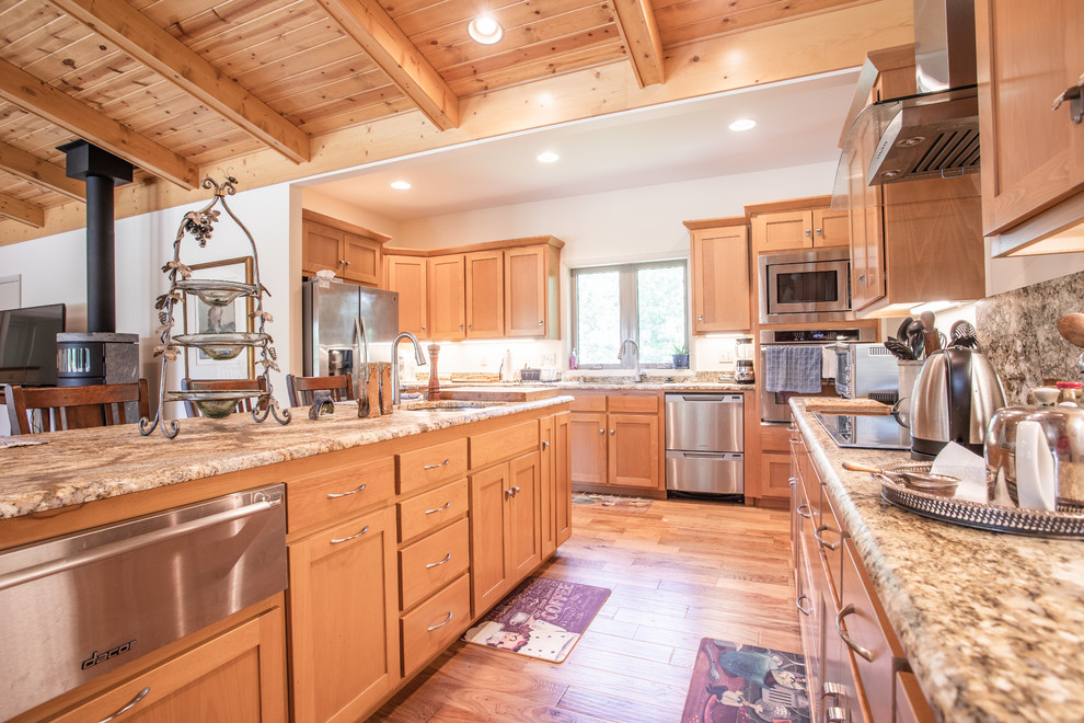 Open concept kitchen - large transitional u-shaped light wood floor and beige floor open concept kitchen idea with an undermount sink, shaker cabinets, light wood cabinets, granite countertops, stainless steel appliances, an island and brown countertops