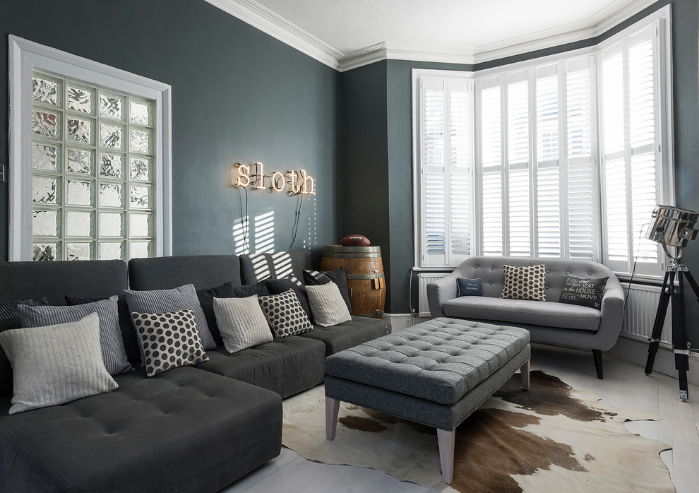 This is an example of a large transitional open concept living room in London with grey walls and a wall-mounted tv.