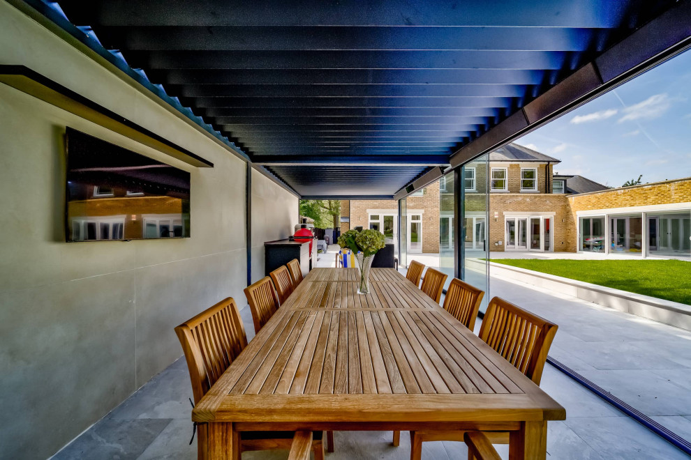 This is an example of a contemporary backyard patio in London with an outdoor kitchen and a pergola.