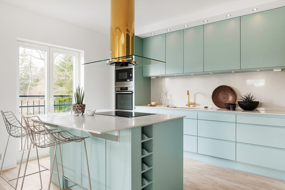 Contemporary galley open plan kitchen in Stockholm with an undermount sink, flat-panel cabinets, turquoise cabinets, white splashback, stainless steel appliances, light hardwood floors, with island and beige floor.