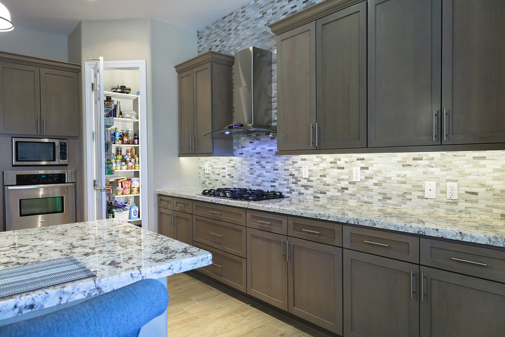 Eat-in kitchen - mid-sized transitional u-shaped laminate floor and beige floor eat-in kitchen idea in Phoenix with a drop-in sink, shaker cabinets, medium tone wood cabinets, granite countertops, beige backsplash, glass sheet backsplash, stainless steel appliances, a peninsula and beige countertops