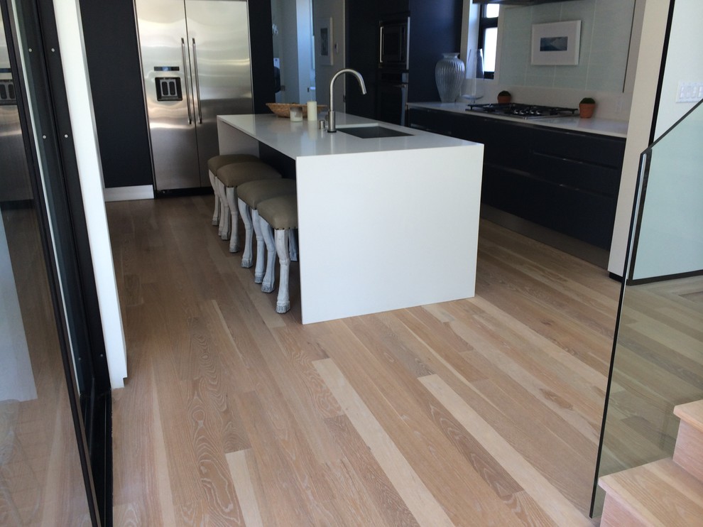 This is an example of a large contemporary l-shaped separate kitchen in Los Angeles with flat-panel cabinets, quartz benchtops, stainless steel appliances, with island, a single-bowl sink, dark wood cabinets, blue splashback, ceramic splashback, light hardwood floors and beige floor.