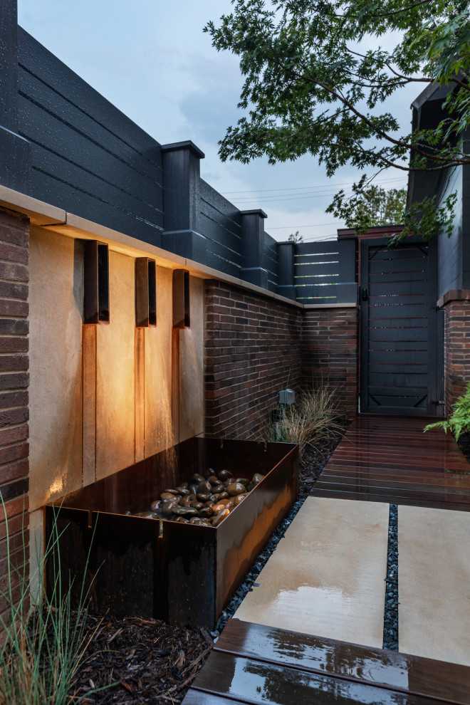 Cette image montre un jardin design avec un point d'eau et une terrasse en bois.