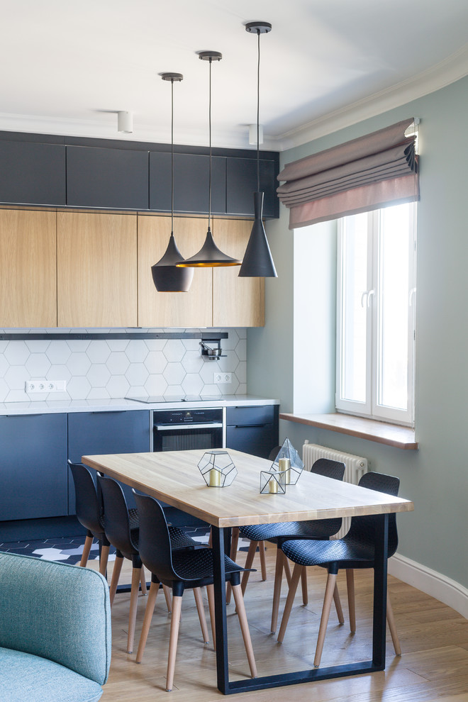 This is an example of a large contemporary single-wall eat-in kitchen in Moscow with an undermount sink, flat-panel cabinets, black cabinets, quartz benchtops, white splashback, ceramic splashback, black appliances, ceramic floors, no island, black floor and white benchtop.