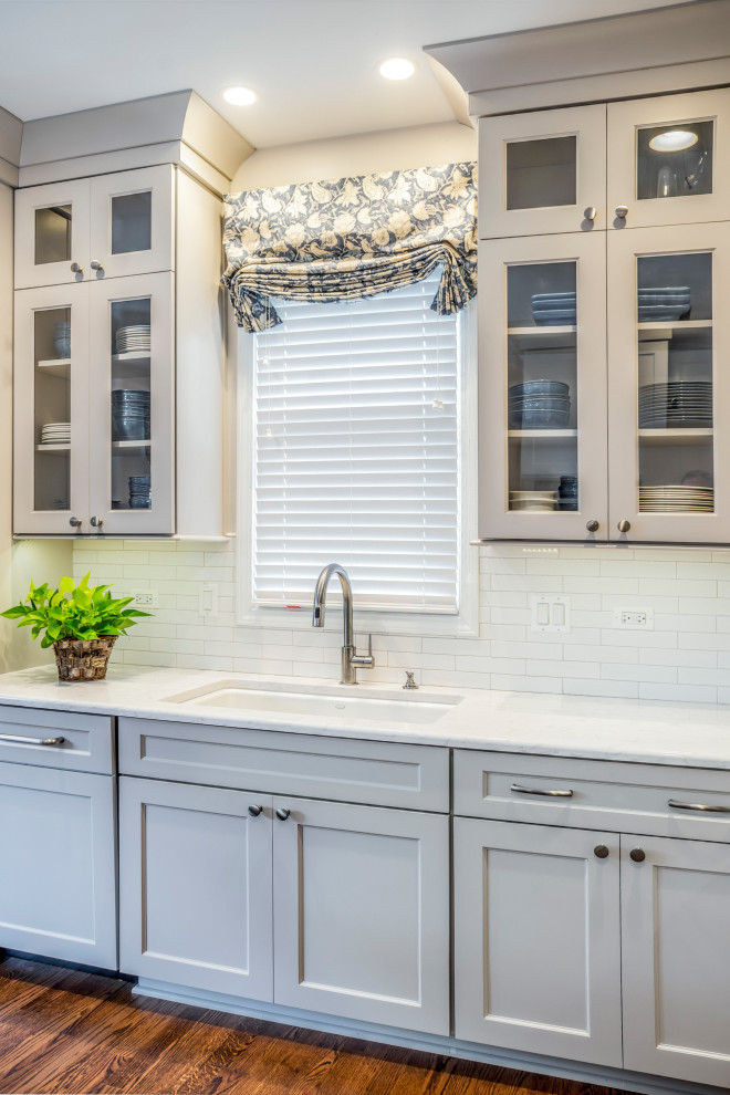 Eat-in kitchen - mid-sized transitional u-shaped medium tone wood floor eat-in kitchen idea in Chicago with an undermount sink, shaker cabinets, gray cabinets, quartz countertops, white backsplash, stone tile backsplash, stainless steel appliances, a peninsula and white countertops