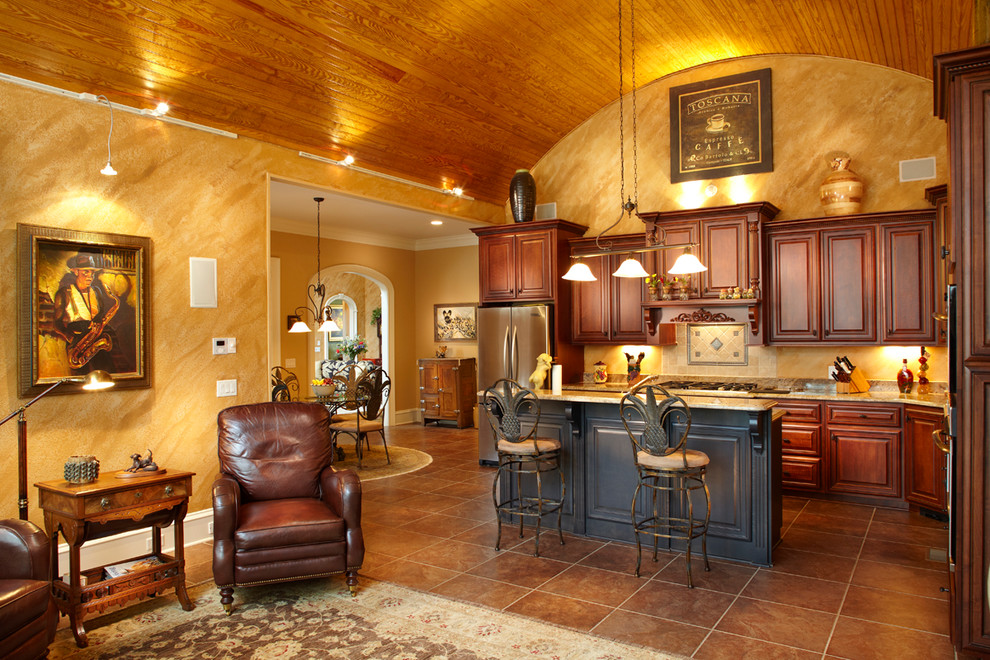 Example of a mid-sized transitional l-shaped travertine floor and brown floor open concept kitchen design with raised-panel cabinets, dark wood cabinets, beige backsplash, stainless steel appliances, an island, a double-bowl sink, granite countertops and stone slab backsplash