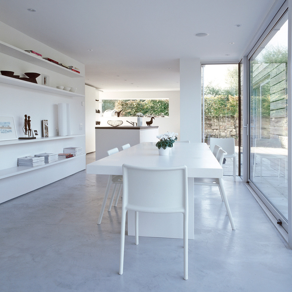 Photo of a mid-sized contemporary dining room in London with white walls and concrete floors.