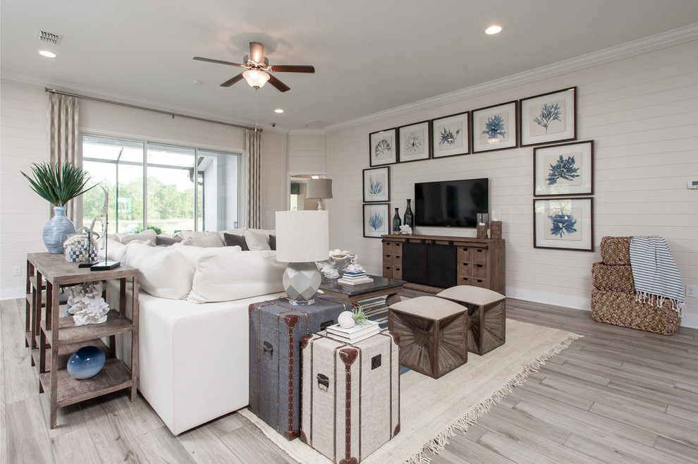 Photo of a large beach style open concept family room in Jacksonville with white walls, ceramic floors, a wall-mounted tv and beige floor.