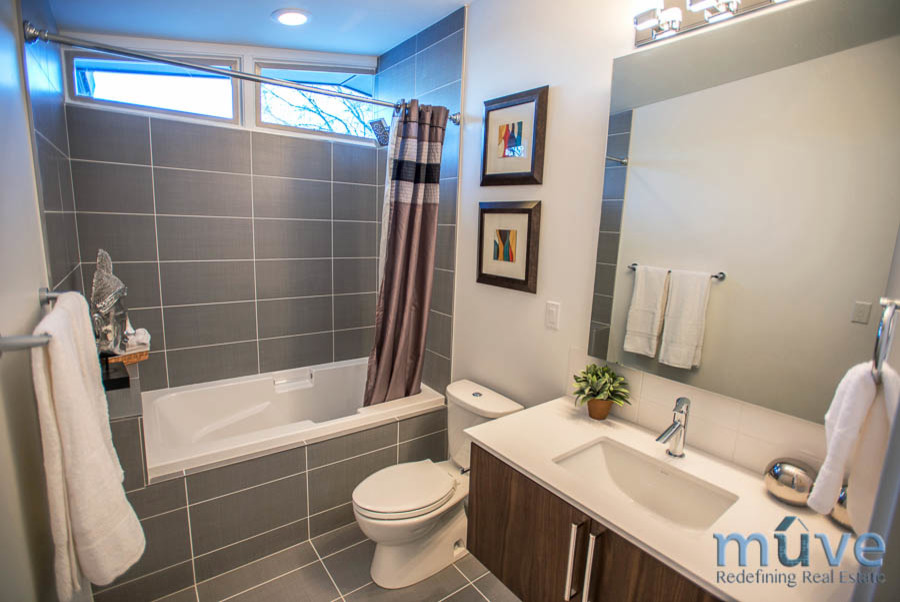 Retro bathroom in Salt Lake City with flat-panel cabinets, brown cabinets, an alcove bath, a shower/bath combination, a two-piece toilet, grey tiles and ceramic tiles.