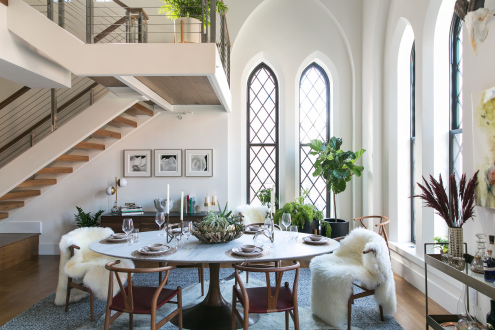 Foto di una sala da pranzo aperta verso il soggiorno contemporanea con pareti bianche, parquet chiaro, pavimento marrone e soffitto a volta