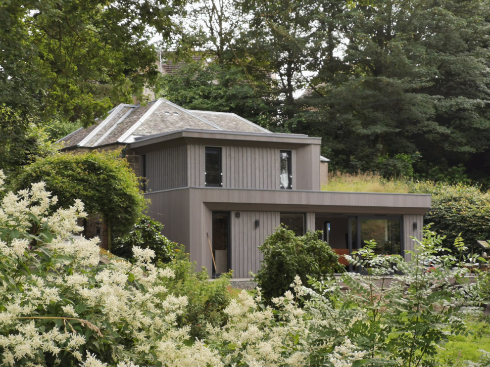 Foto della facciata di una casa grigia contemporanea con rivestimento in legno, tetto piano, copertura verde e pannelli e listelle di legno