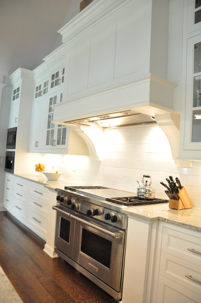 Large transitional l-shaped medium tone wood floor and brown floor eat-in kitchen photo in Cleveland with an undermount sink, recessed-panel cabinets, white cabinets, marble countertops, white backsplash, subway tile backsplash, stainless steel appliances, two islands and white countertops